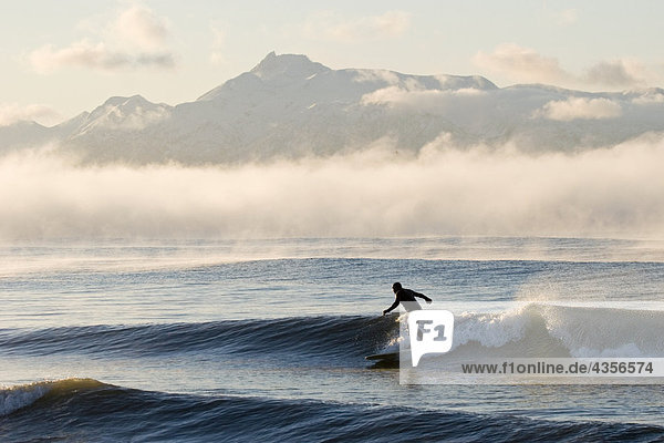 Mann Surfen im Moring in der Nähe von Homer Kachemak Bay w/Kenai Mountains Kenai-Halbinsel in Alaska Winter