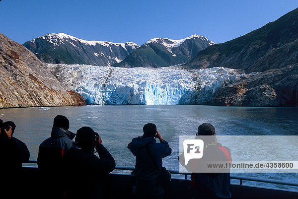 Vistors stand on bow of a boat tour to view Sawyer Glacier in Tracy Arm in Southeast Alaska during Summer