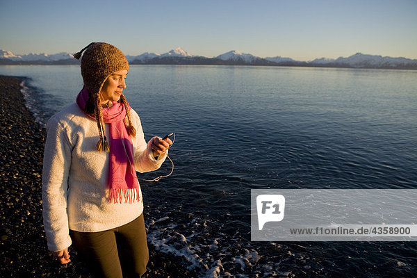 Woman listens to an iPod on Bishops Beach at Kachemak Bay in Homer  Kenai Peninsula  Southcentral Alaska  Winter