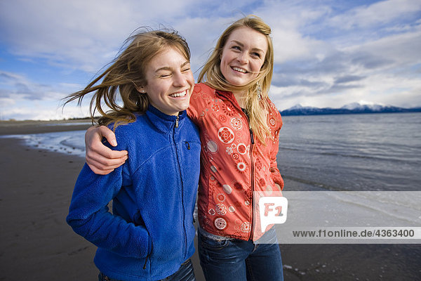 Two young women walk arm in arm at Bishop's Beach in Homer  Alaska