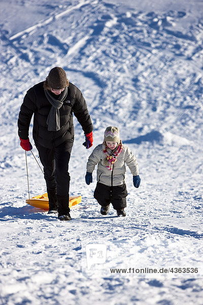 Mother and daughter walking up the sled hill after sleding down it during Winter  Anchorage  Southcentral Alaska