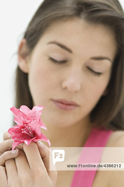 Junge Frau hält rosa Blume  geschlossene Augen