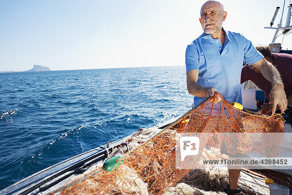 Fischer auf dem Boot beim Einholen von Netzen