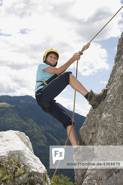 Junge klettert mit einem Seil auf einen Felsen