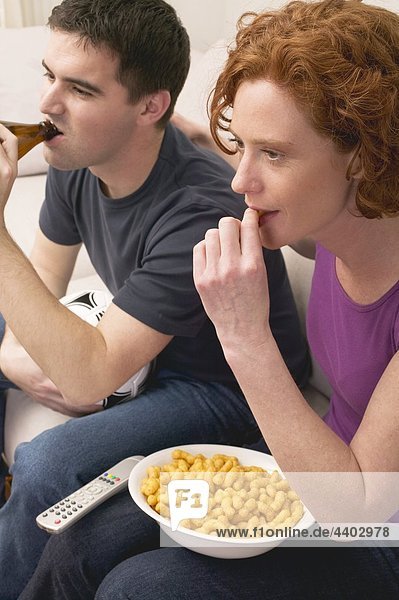 Young couple with football  beer and snack food watching TV