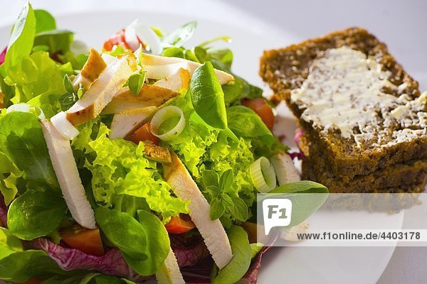 Salat mit Streifen von Hühnerbrust und Vollkornbrot