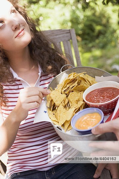 Woman reaching for tortilla chips with two dips in bowl