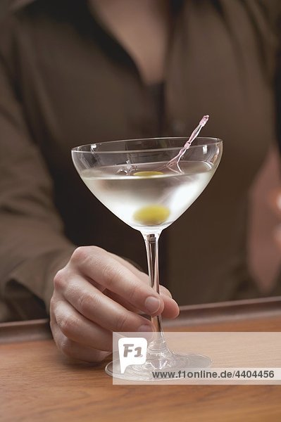 Woman holding glass of Martini with olive