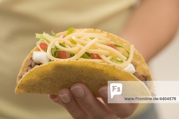 Hand halten einen Taco gefüllt mit Hackfleisch und Käse