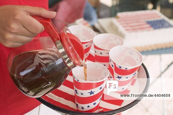 Woman pouring coffee into a paper cup (4th of July  USA)
