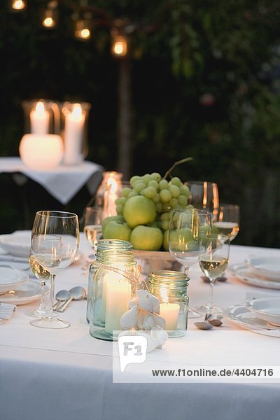 Schüssel Früchte und Windlichter auf Tisch gelegt im Garten