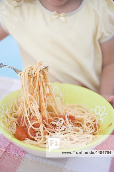 Kleine Mädchen essen Spaghetti mit Tomatensauce und Parmesan