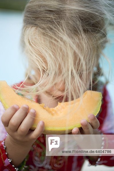 Kleine Mädchen essen ein Stück der Melone