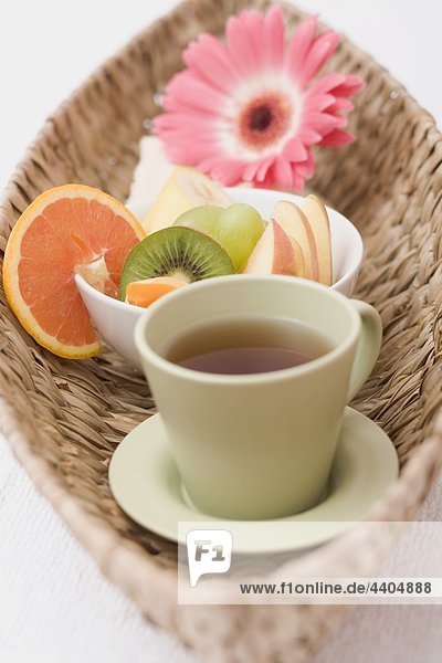 Tasse Tee  frische Früchte  Handtuch und Blumen im Korb