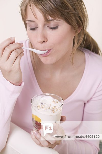 Woman eating yoghurt muesli with fruit