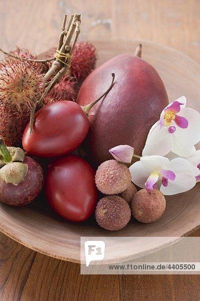 Verschiedene exotische Früchte in ein Gericht mit Orchideen