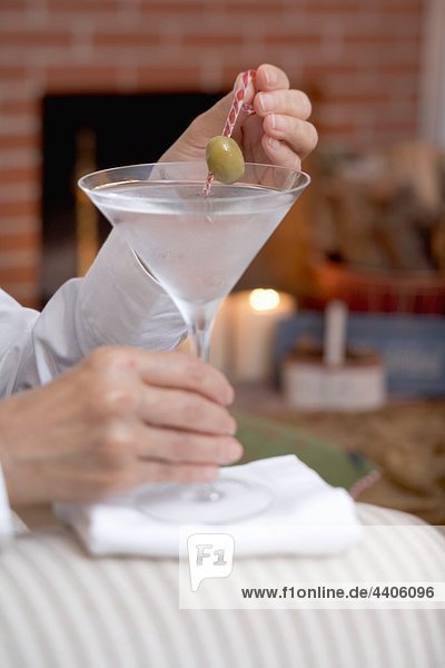 Hände mit Glas Martini mit olive
