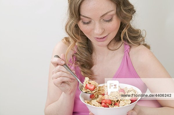 Frau isst Cornflakes mit Erdbeeren