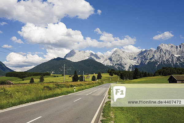 Deutschland  Bayern  Blick auf leere Straße mit Karwendelgebirge im Hintergrund