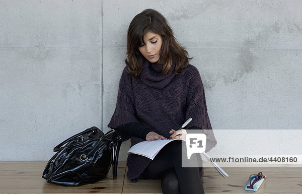 Woman sitting and writing on book