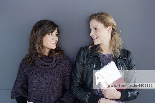 Young women standing face to face  smiling