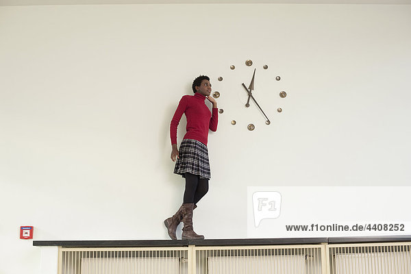 Germany  Leipzig  University student standing and looking at wall clock