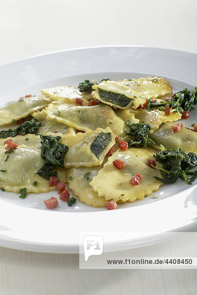 Pasta with spinach and bacon in plate on white background