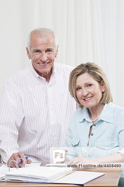 Senior couple doing paperwork  smiling  portrait