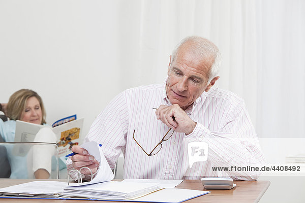 Man doing paperwork with woman sitting in background