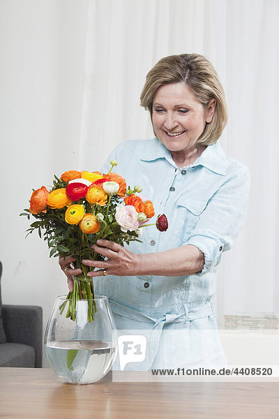 Frau arrangiert Blume in Blumenvase  lächelnd  Portrait