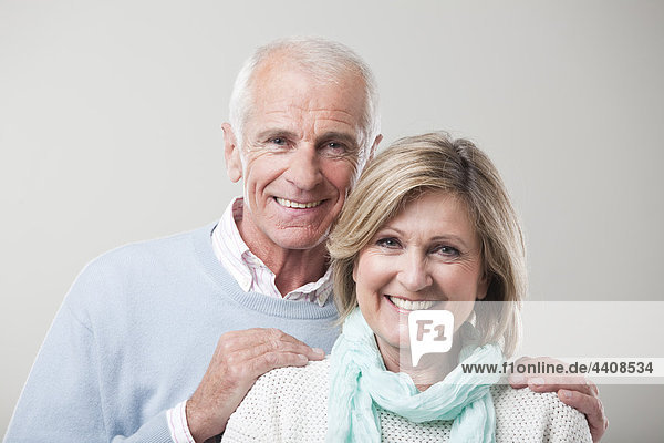 Seniorenpaar vor grauem Hintergrund  lächelnd  Portrait