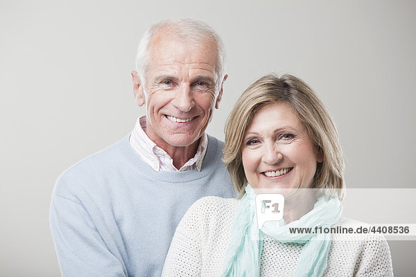 Senior couple against gray background  smiling  portrait