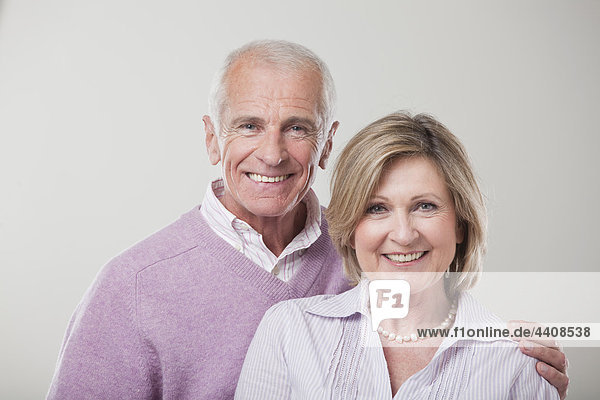Seniorenpaar vor grauem Hintergrund  lächelnd  Portrait