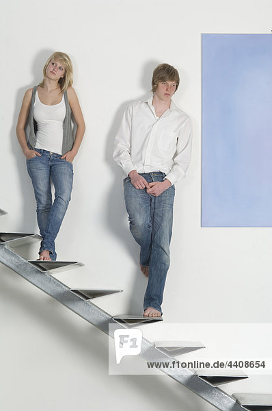 Teenage couple standing on stairway and looking away
