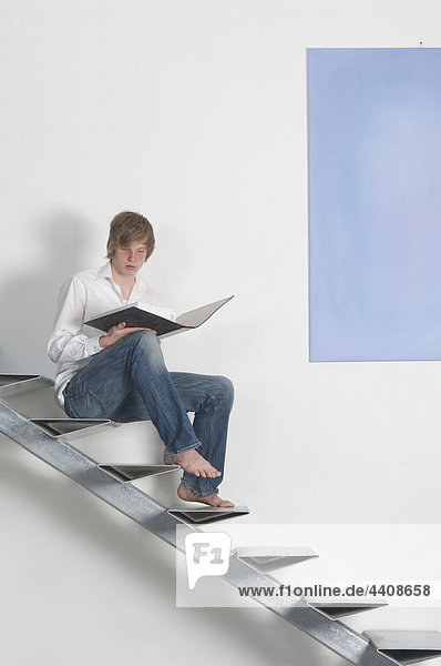 Teenage boy with folder sitting on stairway