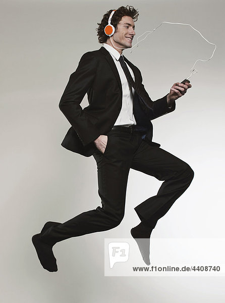 Businessman listening music and jumping  smiling
