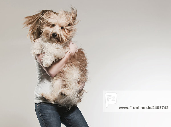 Teenage girl (16-17) holding dog and jumping