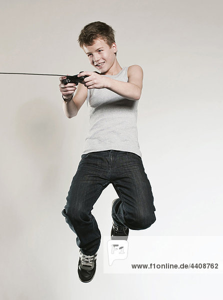 Boy (12-13) playing vedio game and jumping  smiling