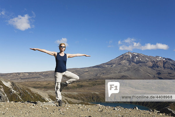 New Zealand  North Island  Woman doing exercise at tongariro national park with mount ruapehu in background