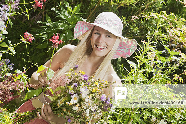 Österreich  Frau im Garten mit Wildblumenstrauß  lächelnd