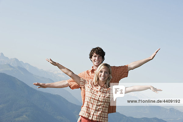 Young couple arms outstreched  smiling  portrait.
