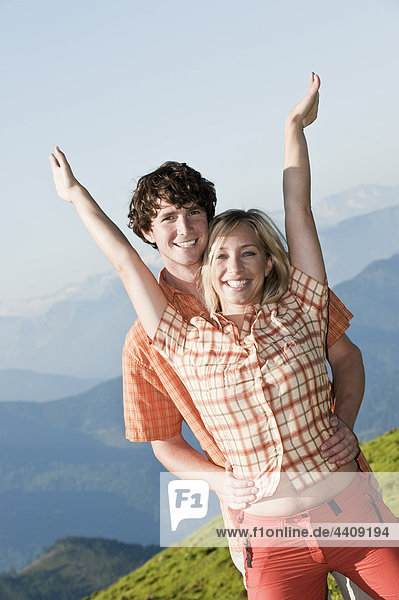 Young couple near mountain  arms up  portrait.