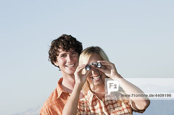 Young couple standing  woman uses binoculars.