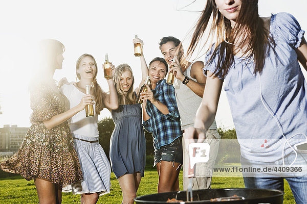 Woman barbecueing with friends in background