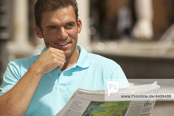 Man sitting with newspaper looking away close up
