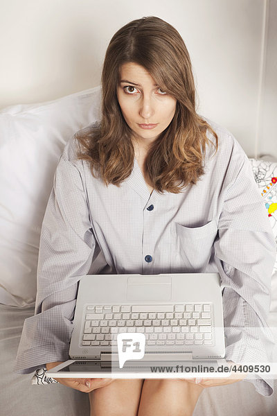 Frau auf dem Bett sitzend mit Laptop  erhöhte Ansicht