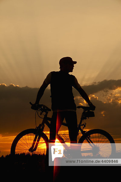 Germany  Lower Bavaria  Biker with bike at sunset