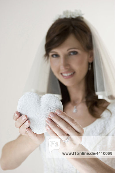 Porträt einer Braut mit herzförmigem Kopfkissen  lächelnd