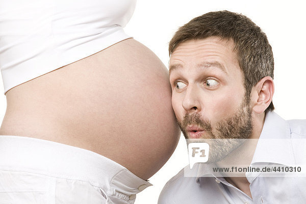 Mann hört auf den Bauch einer schwangeren Frau  Nahaufnahme