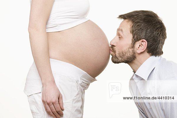 Man kissing pregnant woman's belly  side view